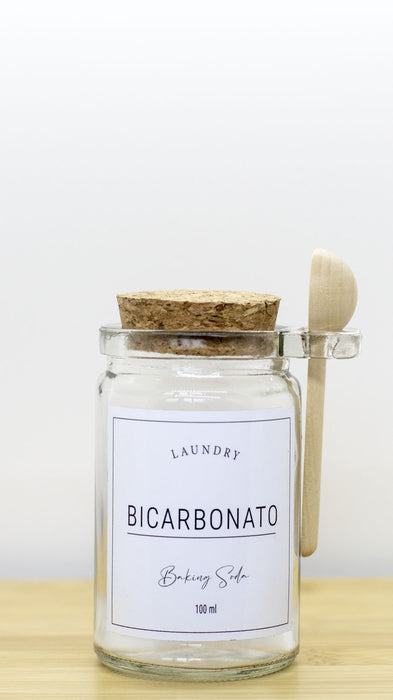 Frasco de vidrio para bicarbonato con tapa de corcho y cuchara de madera.